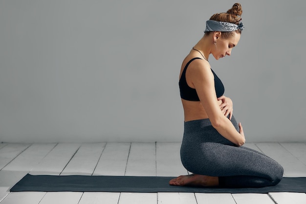 Photo side view of young woman sitting against wall