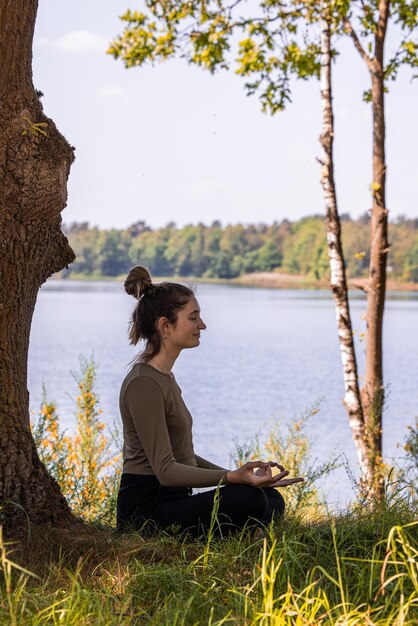 Foto vista laterale di una giovane donna seduta vicino al lago