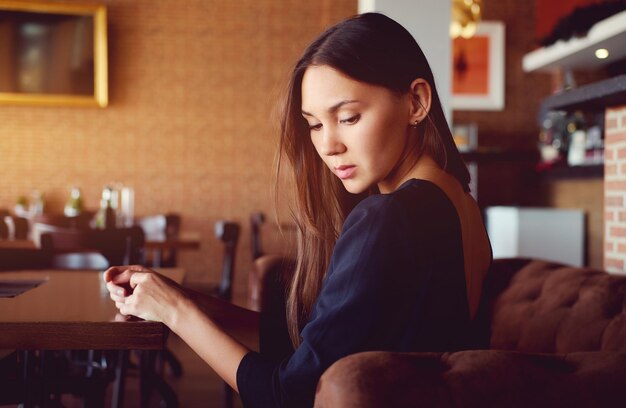 Photo side view of young woman sitting at restaurant