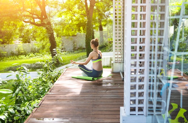 Photo side view of young woman sitting on sidewalk against plants