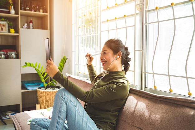 Photo side view of young woman sitting on window at home