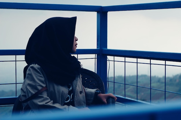 Side view of young woman sitting on window