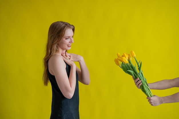 Side view of young woman standing against yellow background