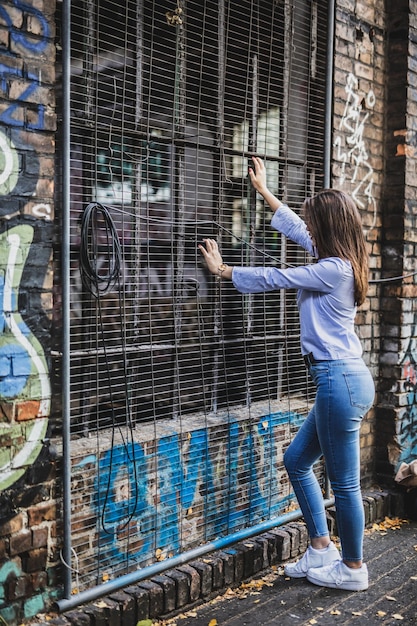 Photo side view of young woman standing by metal grate