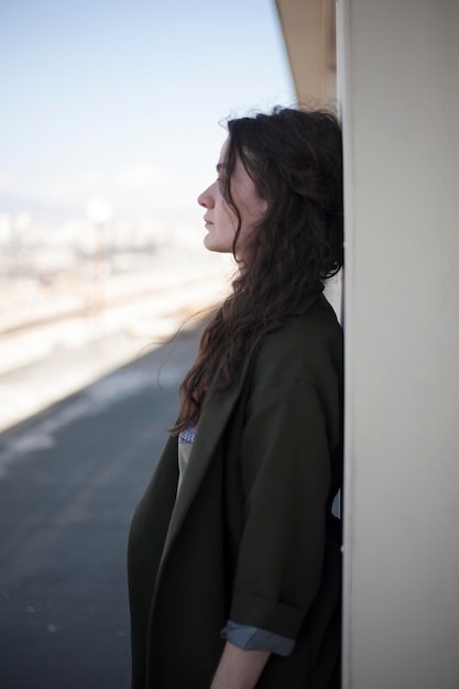 Photo side view of young woman standing by wall