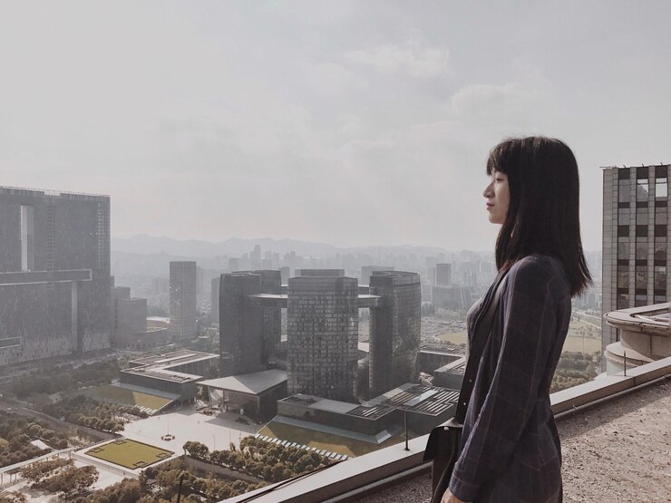 Photo 도시 풍경 을 배경 으로 테라스 에 있는 젊은 여자 의 면