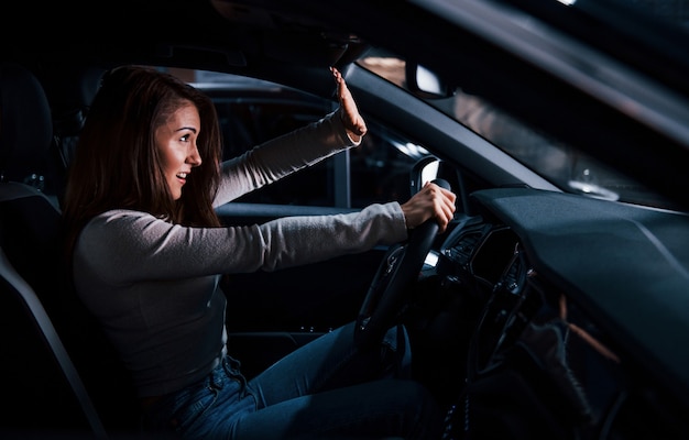 Side view of young woman that inside of brand new modern automobile.