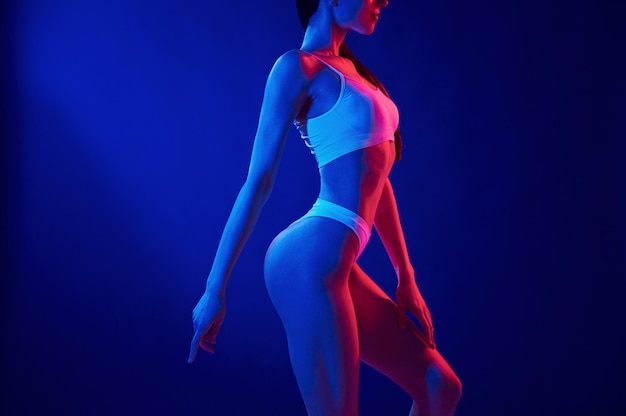 Side view Young woman in underwear is in the studio with neon lights