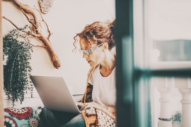 Photo side view of young woman using laptop at home