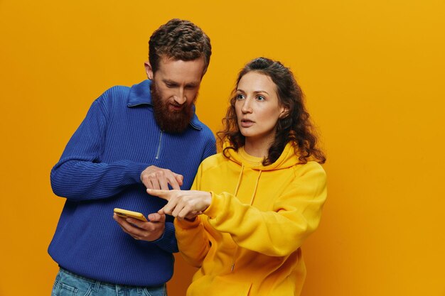 Side view of young woman using mobile phone against yellow background