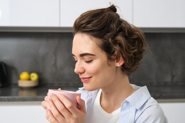 家で携帯電話を使っている若い女性のサイドビュー