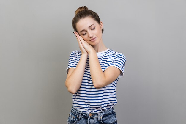 Photo side view of young woman using mobile phone while standing against gray background