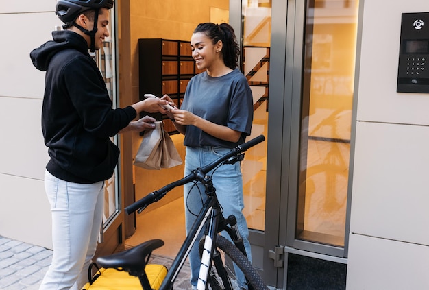 Photo side view of young woman using mobile phone while standing by window