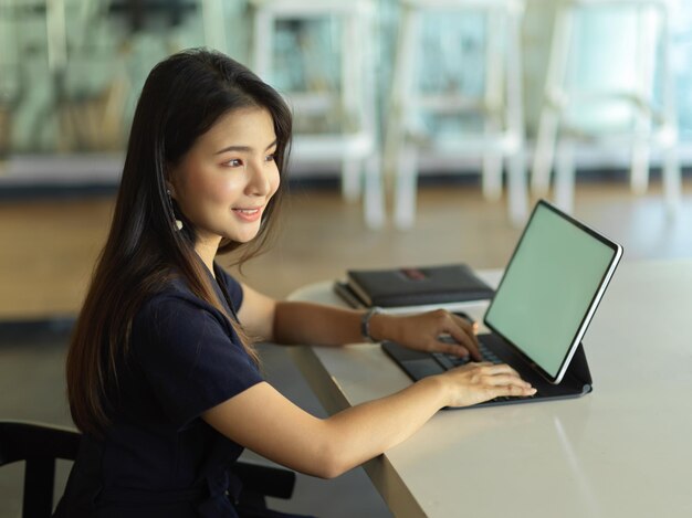 Side view of young woman using phone on table