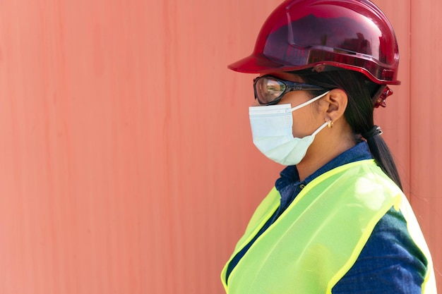 Photo side view of a young woman wearing a protective mask in a factory.