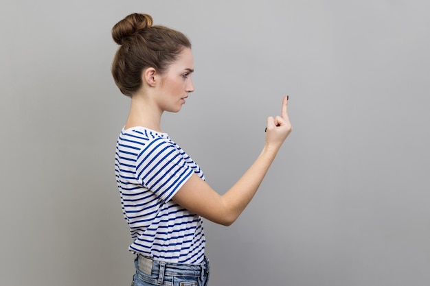 Photo side view of young woman with arms raised standing against wall