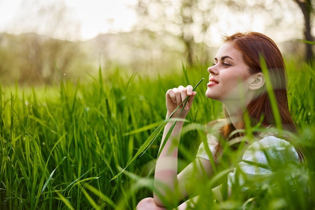 Photo side view of young woman with eyes closed sitting on field