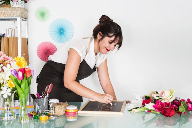 Side view of a young woman writing open word on slate with chalk