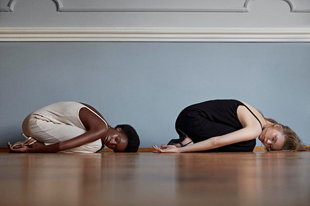 Side view of young women exercising on hardwood floor