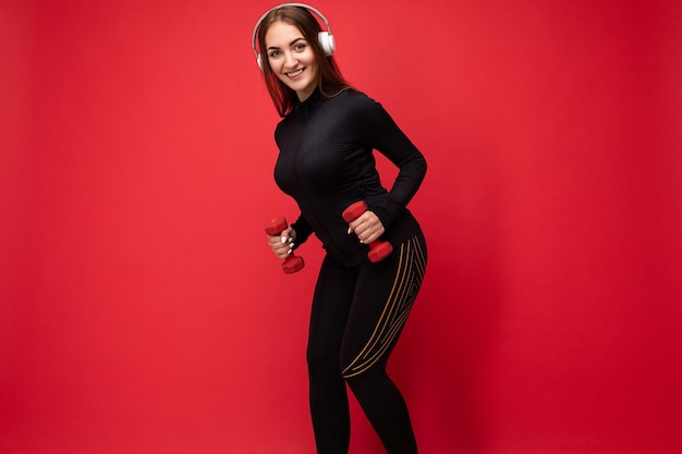 Foto di profilo laterale di una giovane donna bruna sorridente positiva attraente che indossa abiti sportivi neri