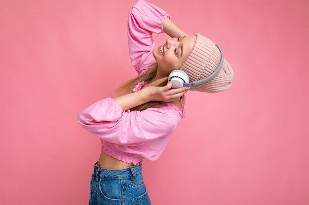 Sideprofile photo of beautiful happy smiling young blonde woman wearing pink blouse and pink hat