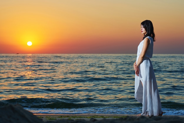 Sideview of young woman on sunset's background.