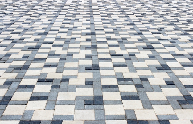 Sidewalk in the park is paved with multicolored stone blocks