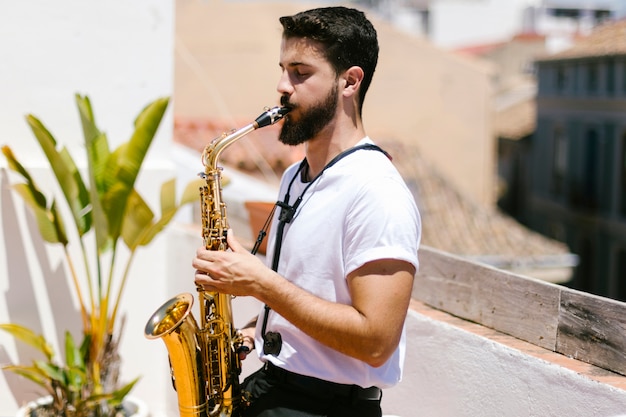 Photo sideways medium shot of man playing the saxophone