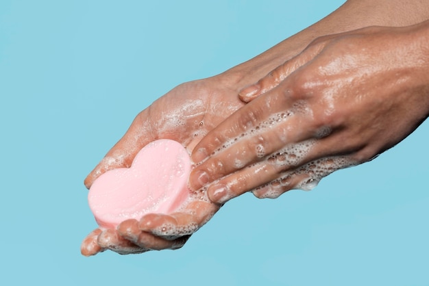 Photo sideways person holding a heart shaped soap