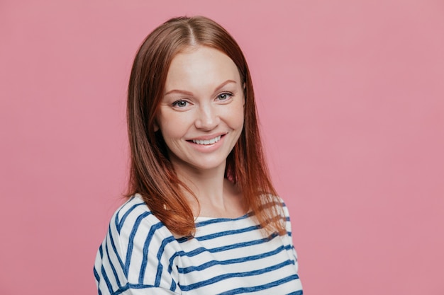 Sideways shot of pleasant looking happy brown haired woman with straight hair