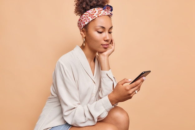 Sideways shot of pretty dark skinned teenage girl reads comments under post in social netwoks