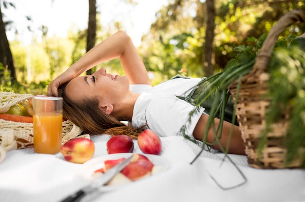 Photo sideways woman having a picnic with healthy snacks
