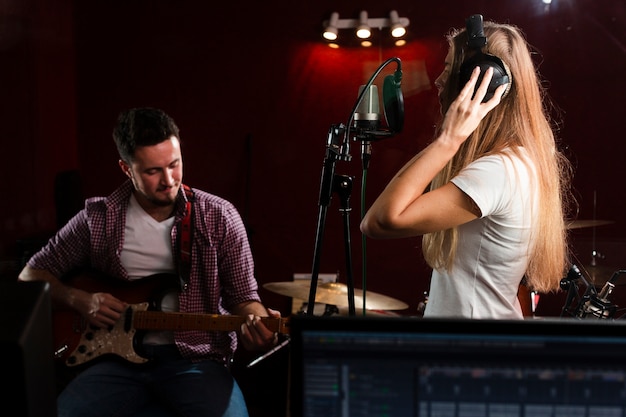 Sideways woman singing and guy sitting with a guitar