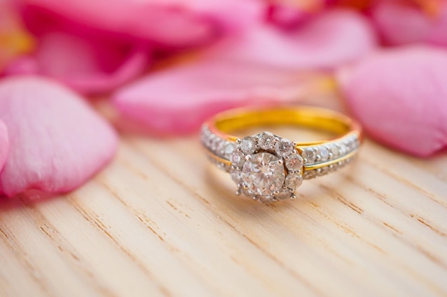 Sieraden diamanten ring op houten tafel met mooie roze rozenblaadjes achtergrond close-up