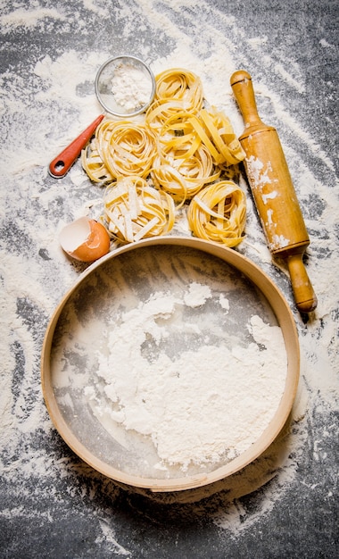 Sift flour and pasta with a rolling pin and eggs. On the stone table. Top view