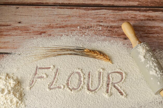 Photo sifted flour on a wooden table with the word flour written on it