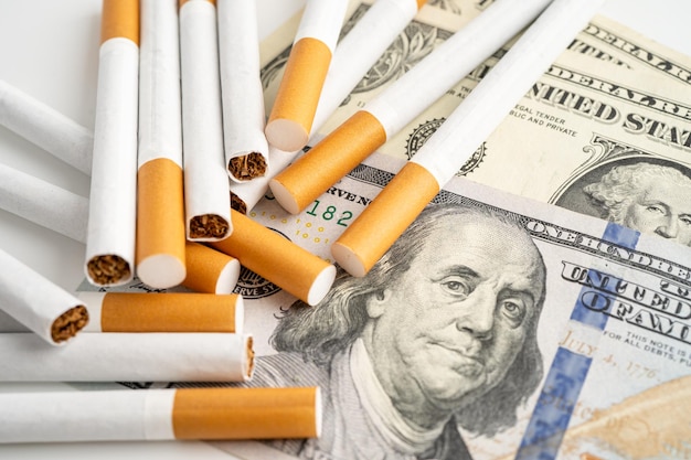 Sigaret op Amerikaanse dollarbiljetten kostenhandel marketing en productie Geen rookconcept