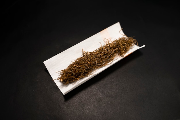 Sigarettenpapier en stapel tabak op zwarte achtergrond