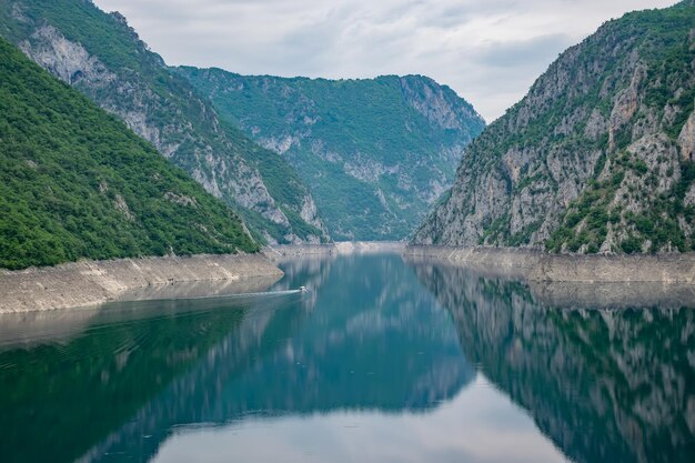 A sightseeing boat with tourists swims along the picturesque lake among the canyon