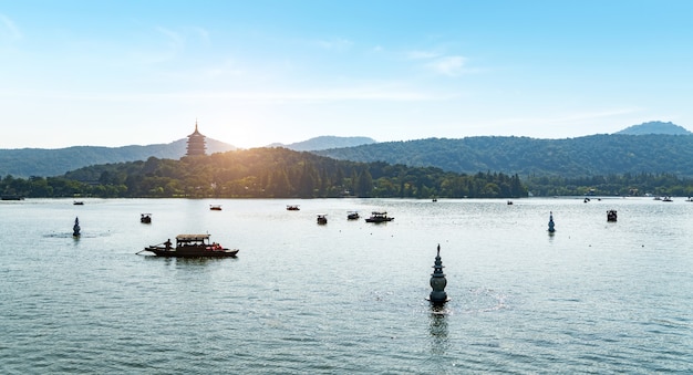 Barche facenti un giro turistico e pagode di pietra e pagode distanti nell'area scenica del lago ad ovest, hangzhou, cina