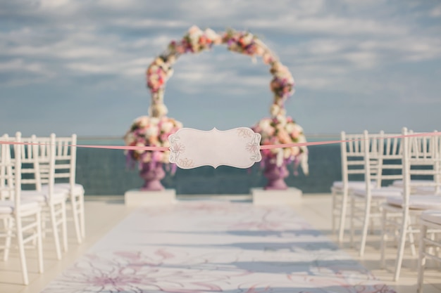 A sign on the backdrop of wedding arch and the sea.