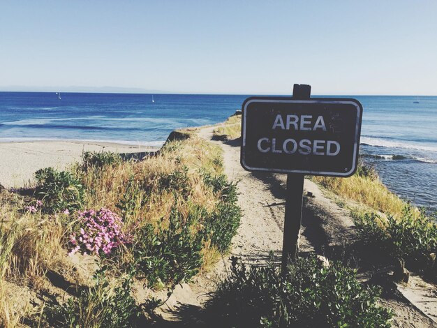 Foto segno sulla spiaggia contro un cielo blu limpido