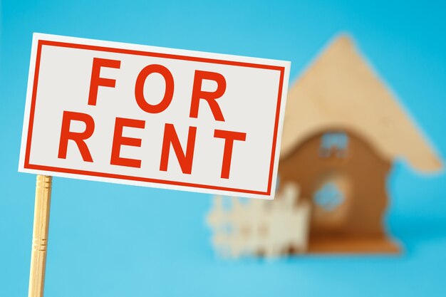 Sign board with text FOR RENT over a house toy