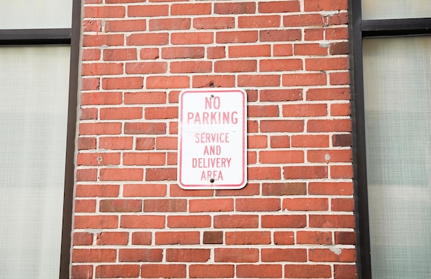 A sign on a brick wall says no parking service and delivery area.