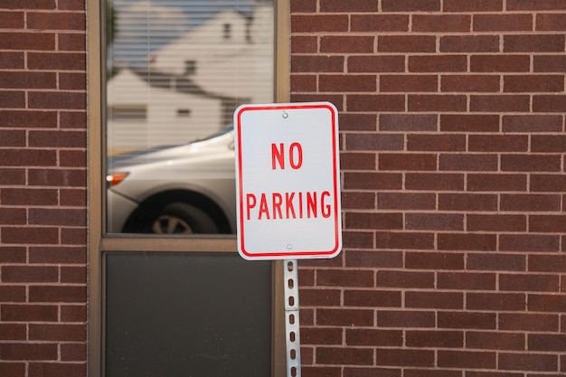 A sign on a pole that says no parking in front of a building.