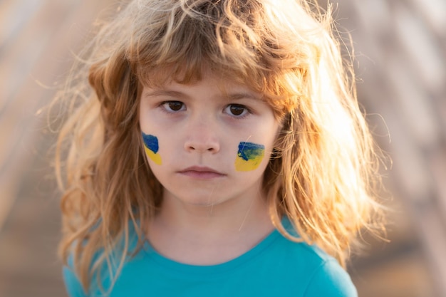 Знак украинского флага на детской щеке маленький ребенок в знак протеста с украинским флагом дети протестуют