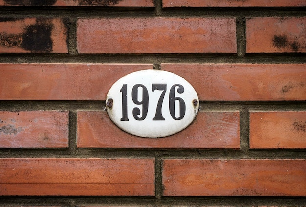 Sign with the house number 1976 on the background of the wall