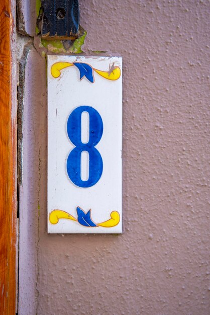 A sign with the number 8 in blue on a pink wall