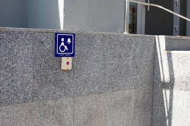 Photo sign with symbol of person in wheelchair near button to call help