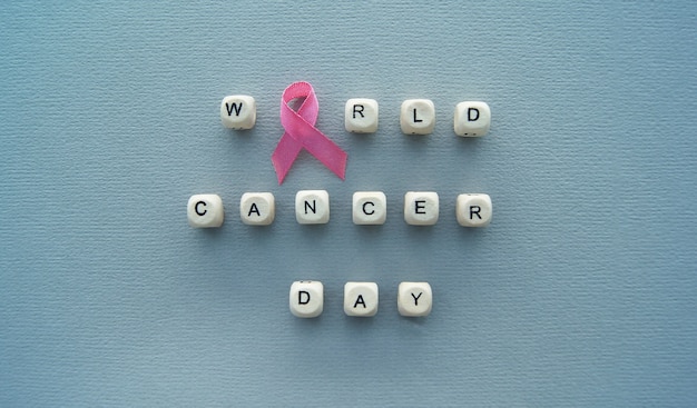 Sign World Cancer Day text and pink ribbon on the grey background.  Prevention and medical concept